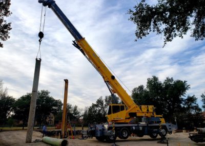 Blue's Crane Service crane stabilized and lifting a pipe.