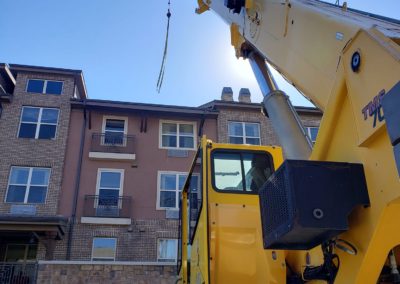 Blue's Crane Service Crane with rigging on it's hook working at an apartment building.