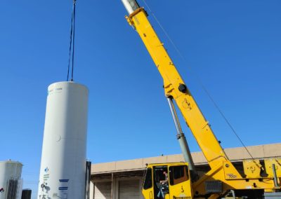 Blue's Crane Service Crane placing a tank with flaggers safely directing the crane operator.