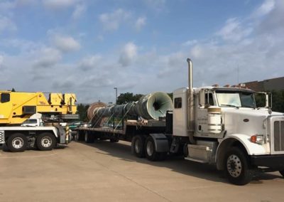 Blue's Crane Service crane about to pick up a lift from a Blue's Hotshot Service flatbed trailer.