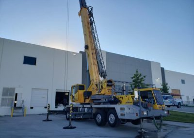 Blue's Crane Service crane ready for a lift in front of a loading dock.