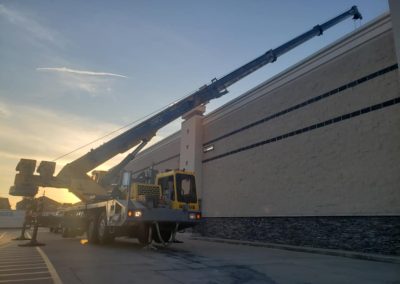 Blue's Crane Service crane stabilized with boom extended over a roof.