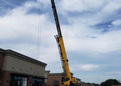 Blue's Crane Service crane ready for a lift in front of a store.