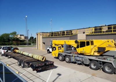 Blue's Crane Service crane in a parking lot next to Blue's Hotshot Service truck and trailer.