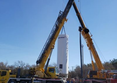 Two cranes lifting a post and a tank for Blue's Crane Service.