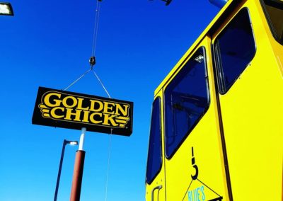 Blue's Crane Service crane placing a Golden Chick sign.