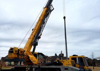 Image of Blue's Crane Service crane setting a post. This image was taken from behind the crane.