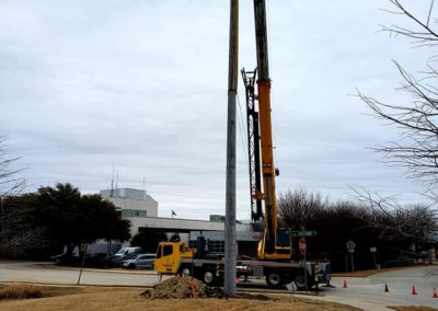 Blue's Crane Service crane setting a post in the ground.